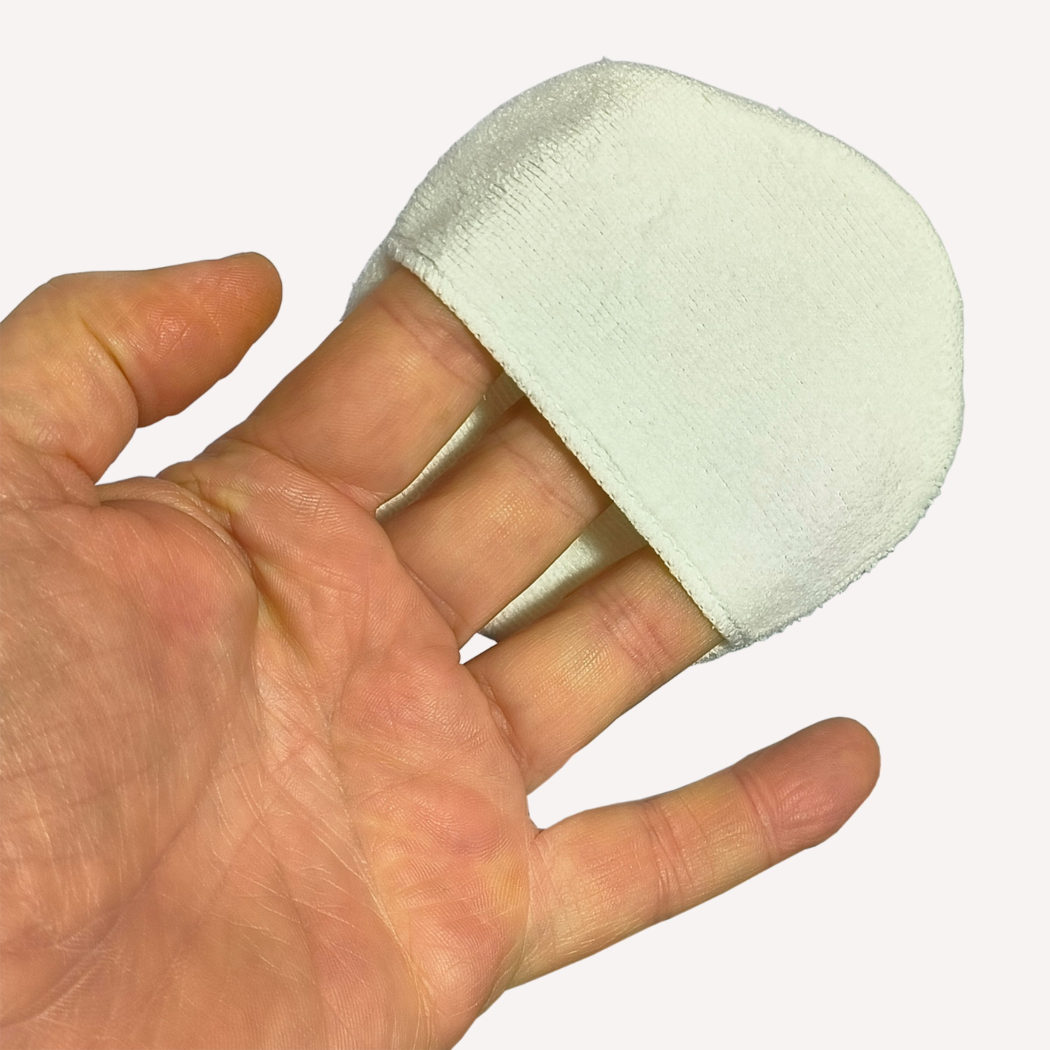 Hand holding white microfibre applicator pad.