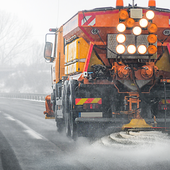 Orange gritter vehicle on frosty road in the UK.