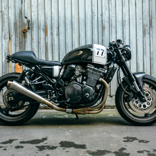 Ablack motorcycle on tarmac ground with a white garage door in the background.